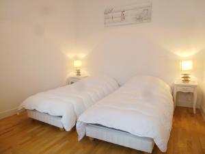 dwa łóżka w pokoju z białą pościelą i lampami w obiekcie Holiday Home Villa Morny by Interhome w mieście Deauville