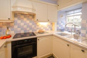 a kitchen with white cabinets and a sink at 2 Bridge Syke, Elterwater in Chapel Stile