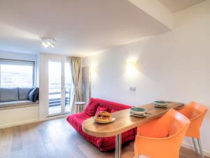 Una sala de estar con un sofá rojo y una mesa. en Apartment Les Marinas-6 by Interhome, en Deauville