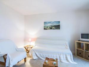 a white bedroom with a bed and a tv at Apartment Baie de Beaumer-1 by Interhome in Carnac