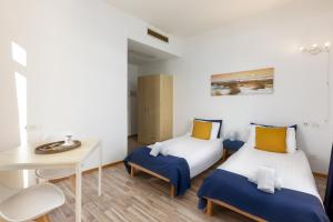 a room with two beds and a desk and a table at GuestHouse Lugano Center by LR in Lugano +81 photos