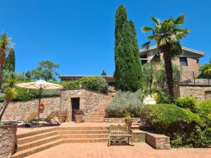 a stone house with a staircase and palm trees at Appartamento L'olivo - Ripabella in Ulignano