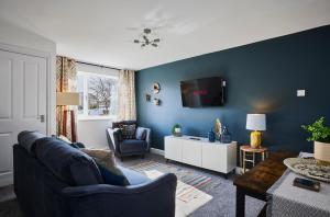 a living room with a couch and a tv on a wall at Charming 2 bed home, quiet village + free parking in Halifax