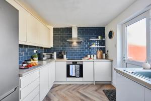 una cucina con armadi bianchi e piastrelle blu di Charming 2 bed home, quiet village + free parking a Halifax