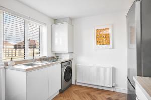 a white kitchen with a washing machine and a sink at Charming 2 bed home, quiet village + free parking in Halifax