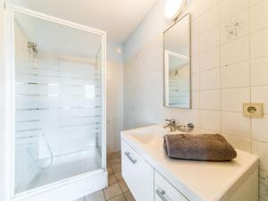 Un baño blanco con ducha y lavabo. en Apartment Ref 602 by Interhome, en Bredene