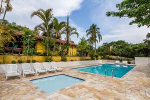 uma piscina com cadeiras brancas ao lado de uma casa em Casa ampla c/ piscina e churrasqueira em Guararema em Guararema