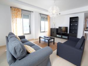 ein Wohnzimmer mit einem blauen Sofa und einem TV in der Unterkunft Apartment Costa Calpe by Interhome in Calpe