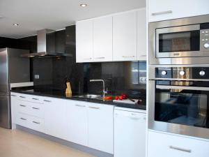 une cuisine avec des armoires blanches et des appareils en acier inoxydable dans l'établissement Apartment Costa Calpe by Interhome, à Calp