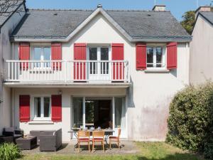 una casa con persianas rojas, mesa y sillas en Holiday Home Les Marines by Interhome en Carnac-Plage