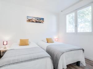 two beds in a white room with a window at Apartment La Cormorane-3 by Interhome in Carnac