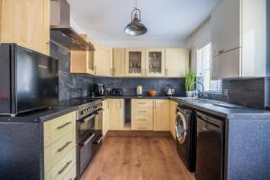 a kitchen with wooden cabinets and a black counter top at Peaceful Home in Central Saundersfoot with Parking in Pembrokeshire