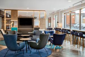 uma área de espera com cadeiras e mesas e um bar em Holiday Inn Express Cambridge West - Cambourne, an IHG Hotel em Cambridge