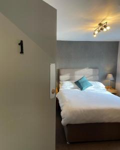 a bedroom with a white bed with a blue pillow at Tollemache Arms in Calveley