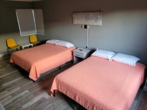 a room with two beds and a table and chairs at Travel Inn Fort Pierce in Fort Pierce