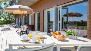 Vacancéole - Les Chambres de la Baie في روز سور كوسنون: طاولة بيضاء مع خبز ومشروبات على الفناء