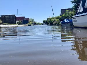 a flooded canal with a boat in the water at Ferienhaus Ankerplatz in Bedekaspel
