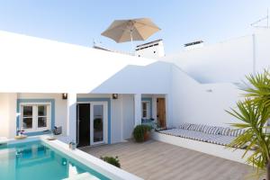 a white house with a swimming pool and an umbrella at Casa da Avó Pam in Alcáçovas
