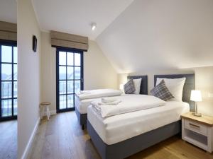 two beds in a room with two windows at Reetland am Meer - Luxus Reetdachvilla mit 3 Schlafzimmern, Sauna und Kamin F15 in Dranske +11 photos