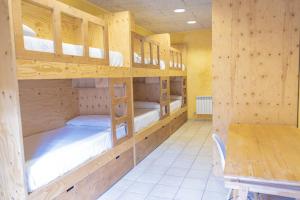 Cette chambre comprend des lits superposés en bois et une table. dans l'établissement La Rectoria d'Albanyà, à Albanya