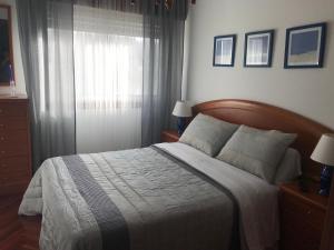 a bedroom with a large bed and a window at Apartamentos turísticos CHUS in A Coruña