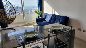 sala de estar con mesa y sofá azul en Antofagasta Sunset - Amplio Departamento con Home Office y Vista Mar, en Antofagasta