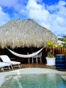 un patio con una sombrilla y sillas de paja y una piscina en Villa Amaryllis luxueuse,piscine,vue mer,plage, en Sainte-Luce