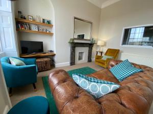 a living room with a brown leather couch and a fireplace at Camden Crescent in Bath