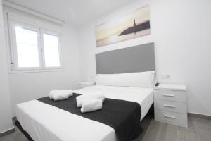 a white bedroom with two beds and a window at For a Stay Roesmar in Cambrils