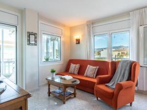 a living room with an orange couch and windows at Apartment Sol i Canal by Interhome in Empuriabrava
