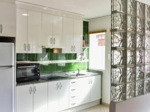 a kitchen with white cabinets and green walls at Apartment Caseta Blanqueta by Interhome in Denia +34 photos