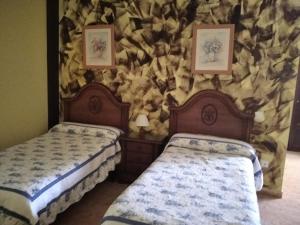 two beds in a room with a stone wall at Pensión Vega de Pas in Comillas