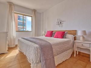 a bedroom with a bed with pink pillows and a window at Apartment Mare Nostrum-1 by Interhome in Calpe