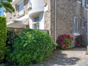 a hedge in front of a building with pink flowers at Apartment L'Abeille d'Or by Interhome in Carnac