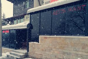 uma estação de comboios na neve em frente a um edifício em Discret Hotel & Restaurant em Vladaya