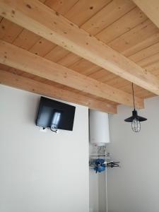 Elle comprend une télévision à écran plat suspendue au plafond en bois. dans l'établissement Little Family, à Salò