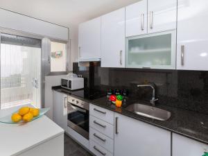 una cocina con armarios blancos y un bol de fruta en la barra en Apartment Meridiano by Interhome, en Miami Platja