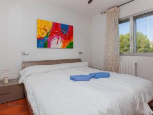 1 dormitorio con 1 cama blanca y una pintura en la pared en Apartment Meridiano by Interhome, en Miami Platja