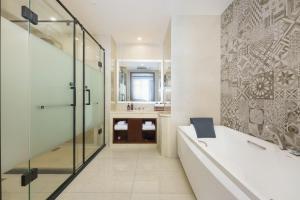 a bathroom with a tub and a glass shower at OBOR Hotel in Ürümqi +16 photos