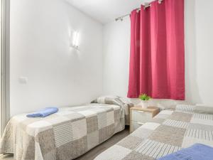 two beds in a room with a red curtain at Apartment Gran Reserva-31 by Interhome in Empuriabrava