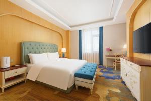 a bedroom with a large bed and a television at OBOR Hotel in Ürümqi