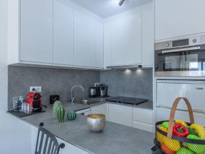 a kitchen with white cabinets and a fruit basket on the counter at Apartment Pattaya-8 by Interhome in Empuriabrava