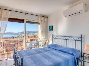 a bedroom with a blue bed and a balcony at Apartment Les Pins Dorés-2 by Interhome in Sainte-Maxime