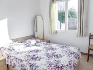 um quarto com uma cama com um edredão floral e uma janela em Holiday Home Philibert by Interhome em Carcans