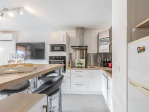 cocina con armarios blancos y barra con taburetes en Apartment Domaine du Préconil-4 by Interhome, en Sainte-Maxime