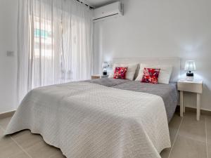 - une chambre blanche avec un grand lit et des oreillers rouges dans l'établissement Apartment Urbatenis-2 by Interhome, à Jávea