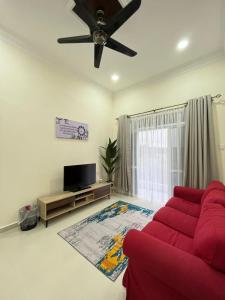 a living room with a red couch and a flat screen tv at Sofea's Homestay in Kuala Terengganu