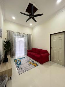 a living room with a red couch and a ceiling fan at Sofea's Homestay in Kuala Terengganu
