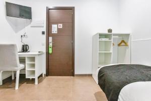 Schlafzimmer mit einem Bett, einem Schreibtisch und einer Tür in der Unterkunft Laramond Barcelona Rooms in Barcelona