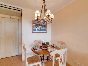 ein Esszimmer mit Tisch und Stühlen und einem Kronleuchter in der Unterkunft Apartment Les Calanques Spa Thalassothérapie-4 by Interhome in Les Issambres + 21 Fotos